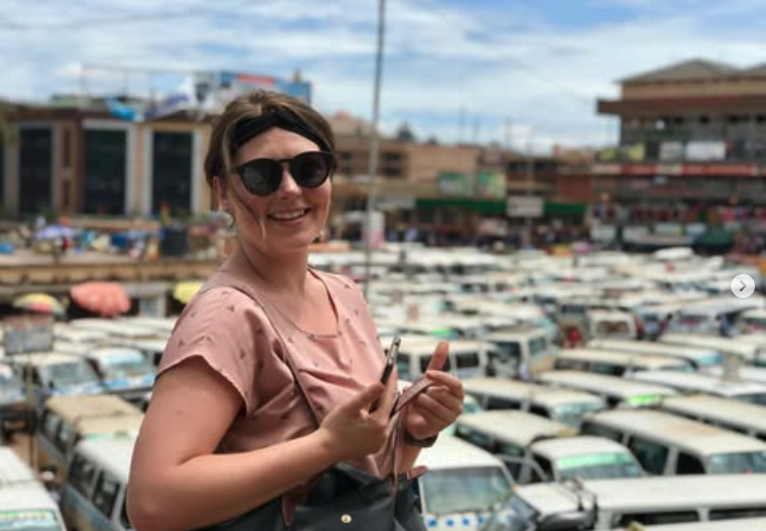 Doll conducting fieldwork in 2023, standing outside a taxi park in Kampala, capital of Uganda.